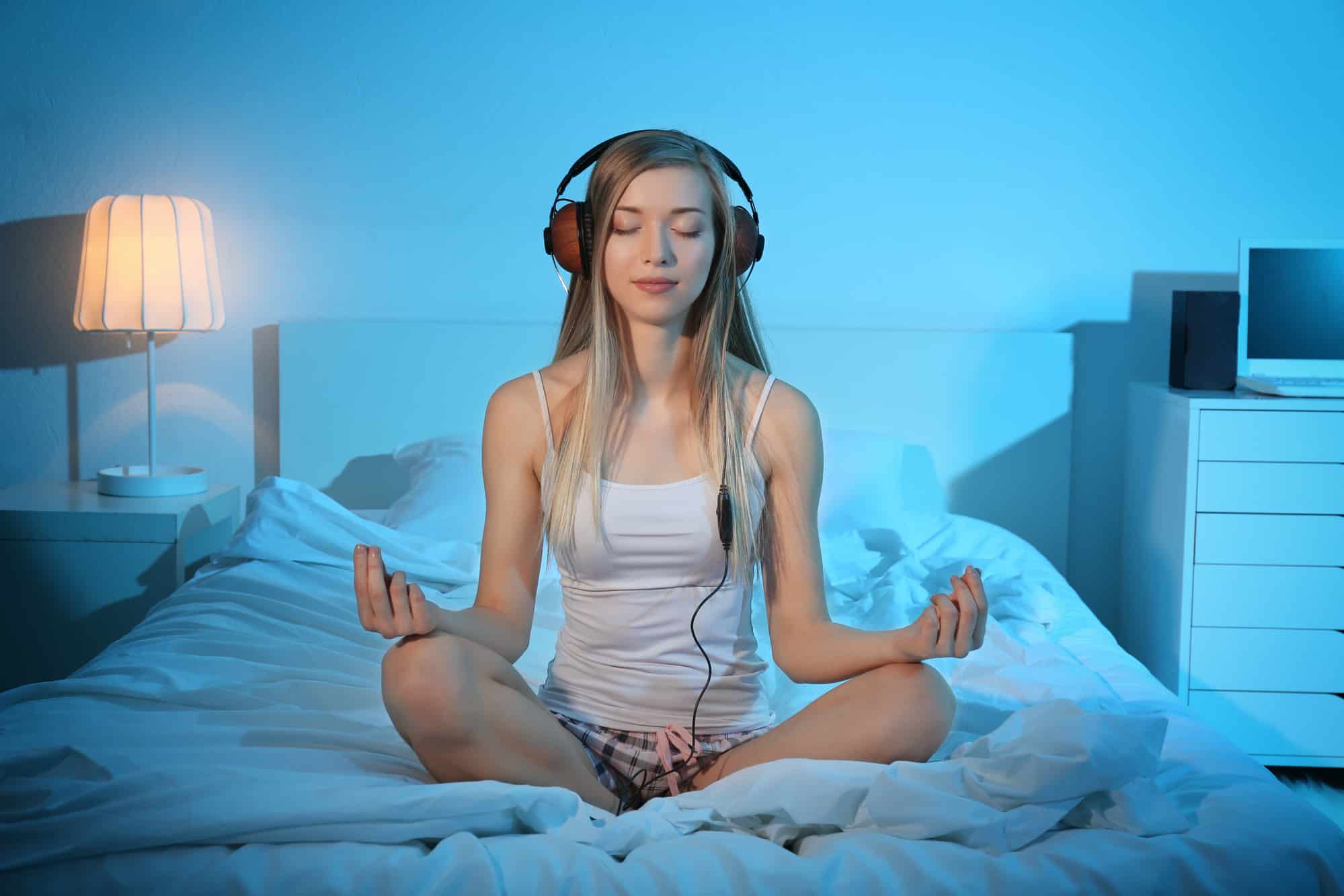 Young woman meditating and listening to music while sitting