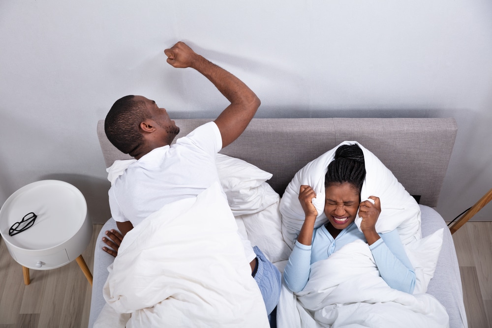 An Overhead View Of Couple Lying On Bed Disturbed By Noise