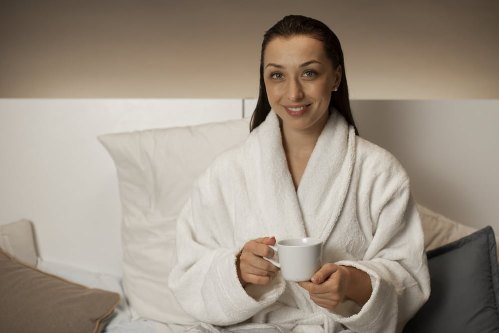 Attractive woman in bathrobe sitting in bed